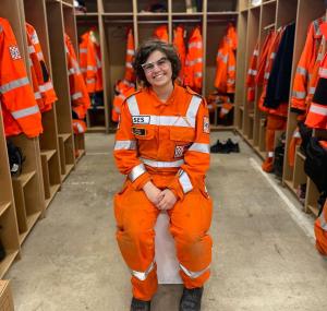 Volunteer Amanda Meuwissen in orange uniform, sitting and smiling at the camera.